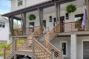 A multi-level residential building with a wooden staircase, outdoor lighting, and potted plants. - 6 King Suites • Heated Saltwater Pool • Dog-Friendly IOP Retreat (Isle of Palms)
