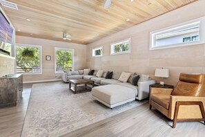 A spacious living room with a large L-shaped sectional sofa, a coffee table, a leather armchair, and a rug. - 6 King Suites • Heated Saltwater Pool • Dog-Friendly IOP Retreat (Isle of Palms)