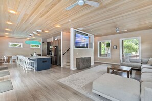 A spacious living area with a kitchen, a dining area, and a large TV mounted on the wall. - 6 King Suites • Heated Saltwater Pool • Dog-Friendly IOP Retreat (Isle of Palms)