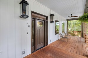 A wooden deck with a door, two wall-mounted lanterns, and a ceiling fan.