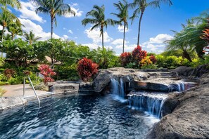 Una località turistica tropicale con piscina naturale, cascate a gradoni e vegetazione rigogliosa.