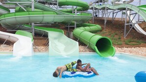 A water park with multiple water slides and a pool area where people are enjoying water activities. - Starbal (Es Castell)
