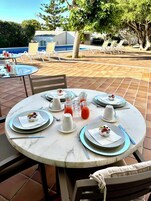 Una mesa redonda dispuesta para una comida, con platos, cubiertos y un vaso de jugo.