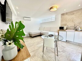 Una cocina moderna con mesa de comedor de vidrio, electrodomésticos blancos y un ventanal grande.