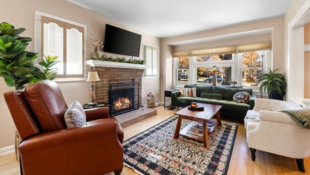A living room with a fireplace, leather chairs, a green sofa, and a television mounted on the wall. - The American Dream: Historic S Mt Vernon Craftsman (Prescott)