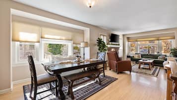 A spacious living room with a large wooden dining table, comfortable seating, and a fireplace.