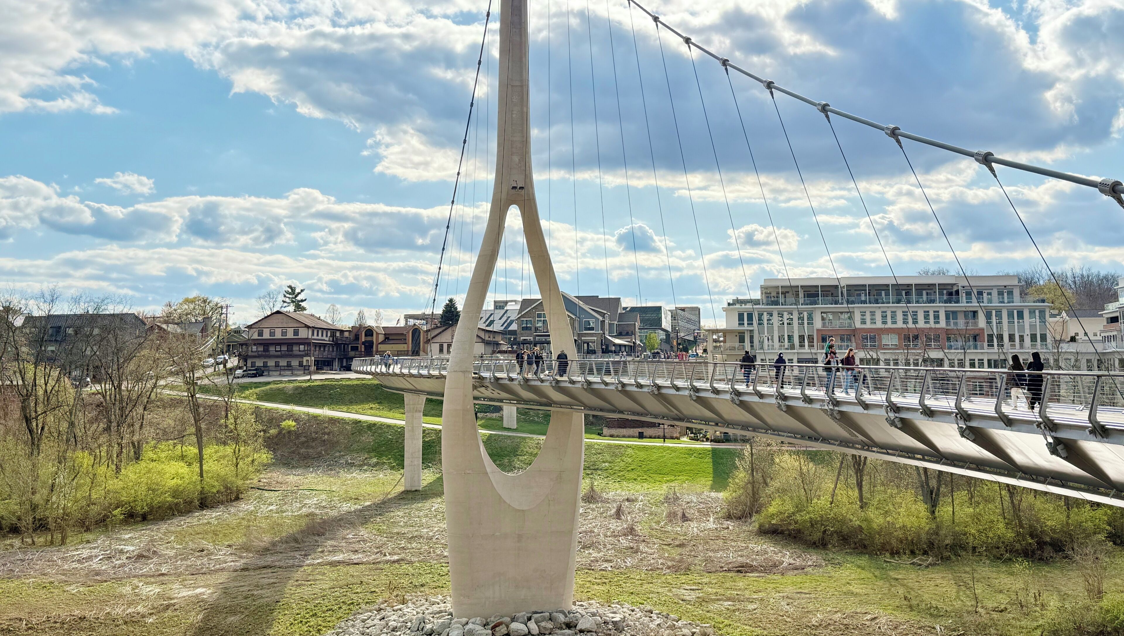 A pedestrian bridge with a unique architectural design, featuring a central support structure and a series of cables.