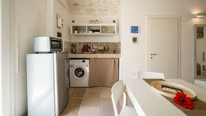 A compact kitchen with a washing machine, a microwave, and a small refrigerator. - Velvet Home: charming studio in the heart of center Ostuni (Ostuni)