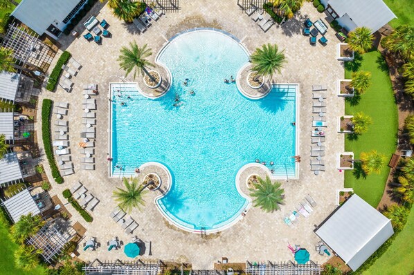 An aerial view of a swimming pool surrounded by lounge chairs and palm trees.
