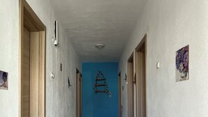 A hallway with a blue accent wall, wooden doors, and a ceiling light fixture. - Zeytin Pansiyon Palamutbükü (Datca)