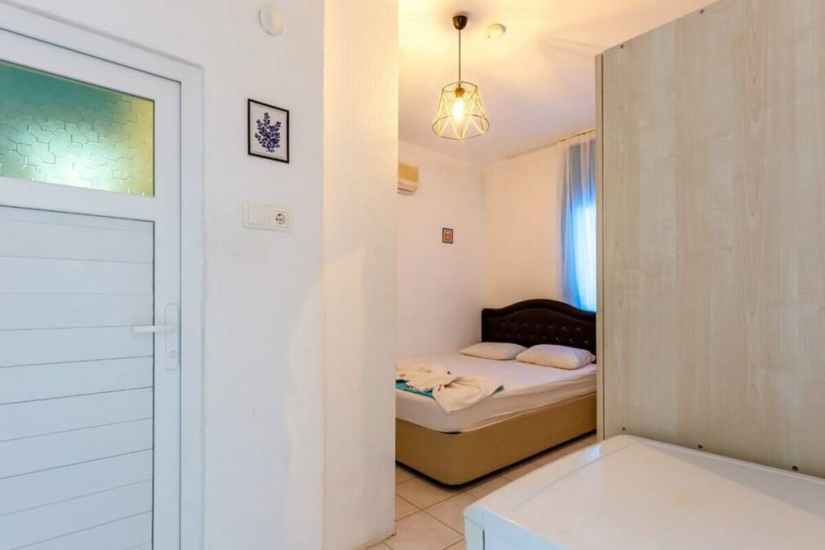 A bedroom with a bed, a bedside table, a hanging light fixture, and a door with frosted glass.
