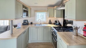 A compact kitchen with a sink, stove, and cabinets.