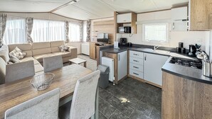 A compact RV interior with a kitchenette, dining area, and living space.