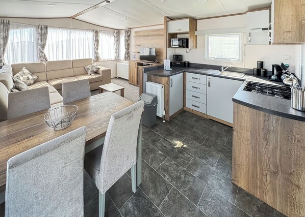 A compact RV interior with a kitchenette, dining area, and living space.