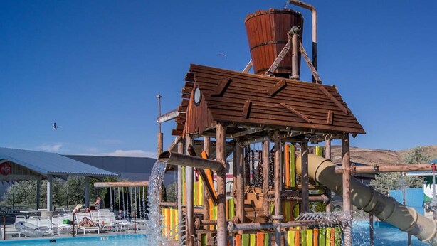 Un parc aquatique doté d’une structure de jeux en bois, d’une piscine et d’un grand toboggan aquatique.