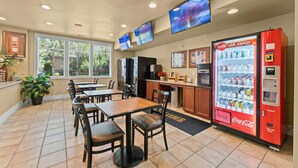 Un restaurant avec des tables, des chaises, un distributeur de Coca-Cola et un espace cuisine.