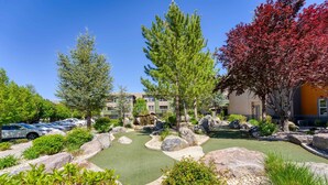Un jardin aménagé avec un petit étang, entouré de gros rochers et de divers arbustes.