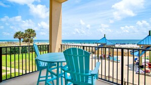 A balcony with turquoise Adirondack chairs, a view of the beach, and a clear sky. - Beachfront 1BR @ Phoenix V • Sleeps 4 • Pools, Hot Tub & Pirate Splash Pad (Orange Beach)