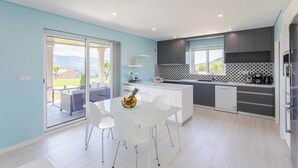 Een moderne keuken met een eethoek, grote ramen en uitzicht op de omgeving.