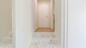 A narrow hallway with a wooden floor and white walls, leading to a closed door. - HostWise - Douro Villa - Suite Teixeira Pascoares (Santa Marinha do Zêzere)