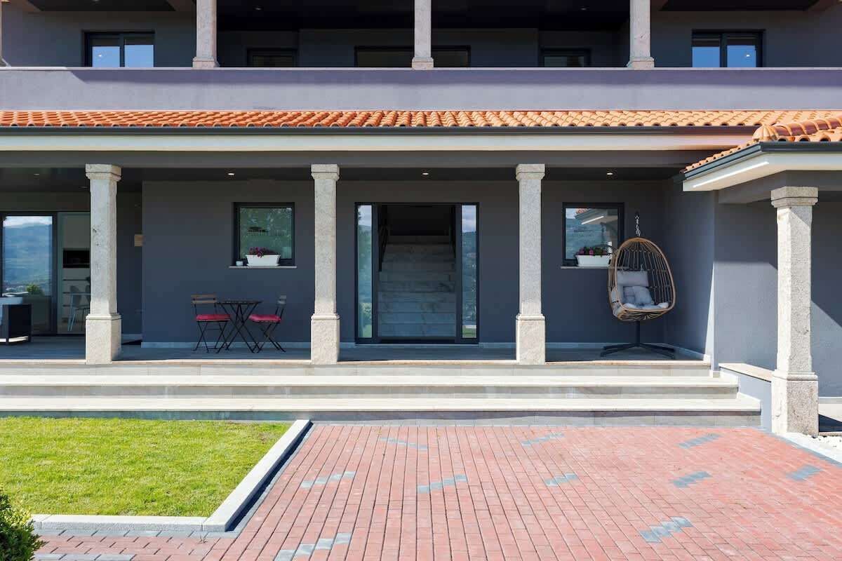 Edifici de dues plantes amb un porxo cobert que inclou una zona d'estar i una cadira penjant.