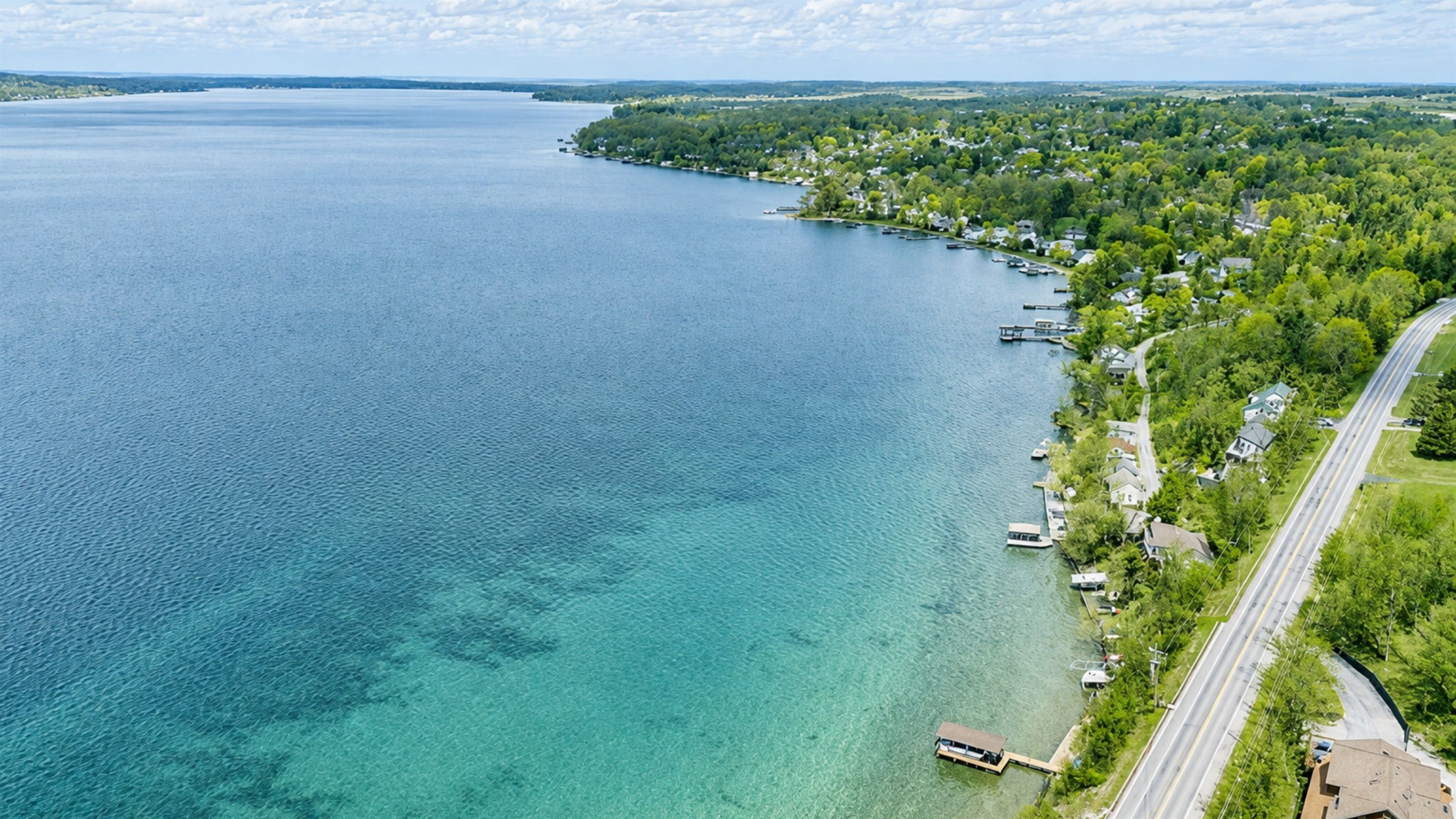 An aerial view of a lakeside community with houses, docks, and a road along the shore.