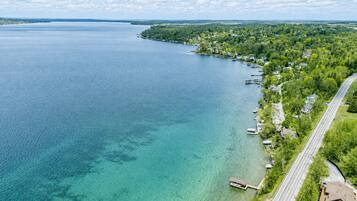 An aerial view of a lakeside community with houses, docks, and a road along the shore.