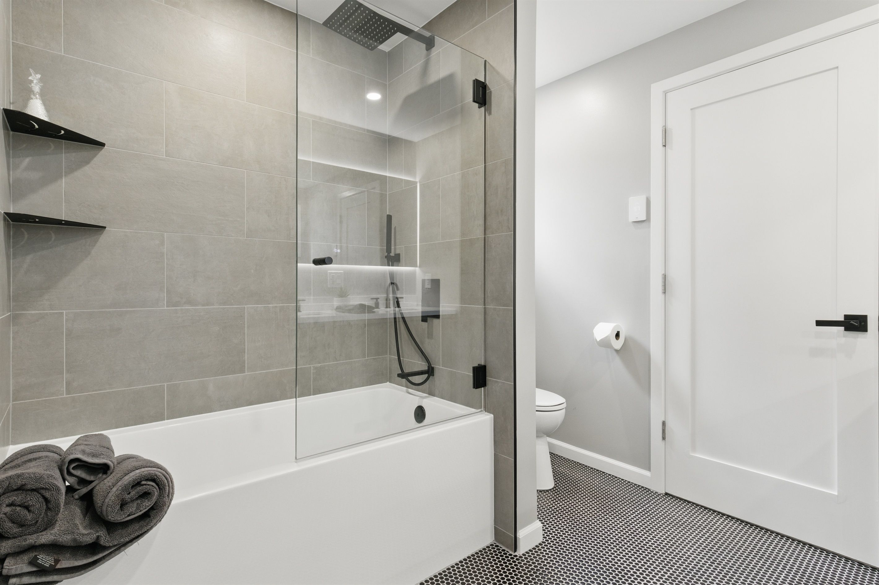 Ein modernes Badezimmer mit einer Duschkabine, einer weißen Badewanne und einer Toilette.