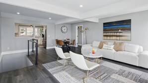 A modern living room with a white sofa, two white chairs, a round coffee table, and a painting on the wall. - Canandaigua Lakefront | Dock | Fire Pit | Kayaks (Rushville)
