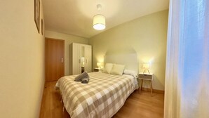 A bedroom with a bed, bedside tables, a wardrobe, and a ceiling light.