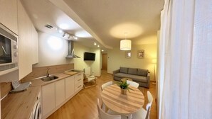 A modern kitchen with a built-in oven, a sink, and a dining area with a round table and chairs.