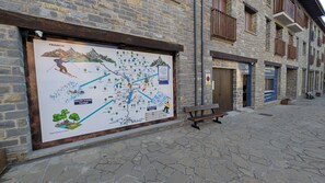 Un edificio de piedra con un gran mapa en la pared, un banco y una puerta.