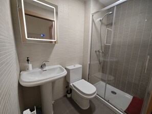 A bathroom with a sink, toilet, and glass-enclosed shower.