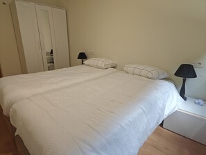A bedroom with a bed, two bedside lamps, a nightstand, and a wardrobe.