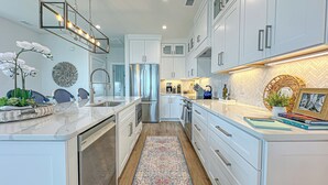 A modern kitchen with white cabinetry, stainless steel appliances, and a herringbone-patterned backsplash.
