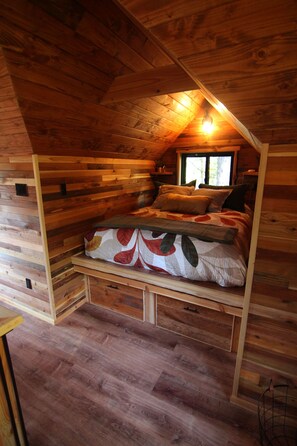 Cozy cabin-style bedroom with a single bed, floral-patterned bedspread, and wooden bench.