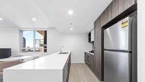 Een moderne keuken met een groot eiland, roestvrijstalen apparatuur en uitzicht naar buiten.