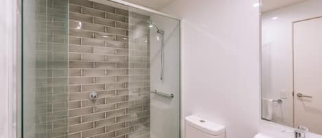 A modern bathroom with a glass-enclosed shower, a white sink, and a toilet.