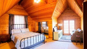 A log cabin bedroom with a bed, a desk, a chair, and a sofa.