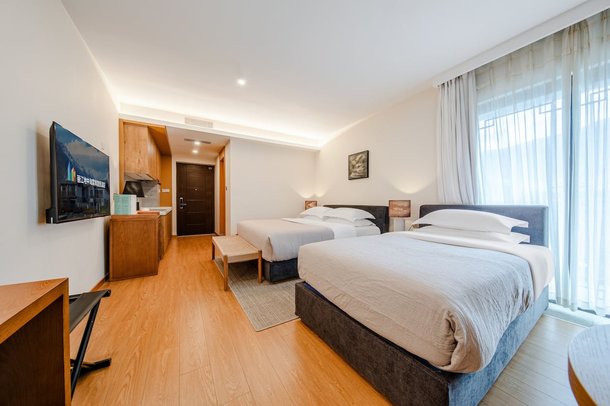 Una habitación de hotel con una cama grande, un escritorio, una silla, una mesita y un banco.