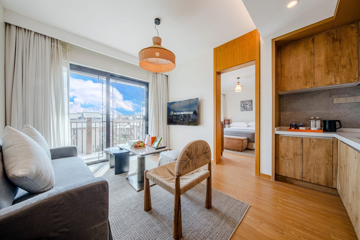 Una sala moderna con un sofá, una silla, una mesa de comedor y una cocina con armarios de madera y encimera.