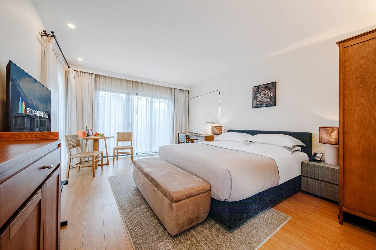 Habitación de hotel con una cama grande, un escritorio con silla, televisión y armario.