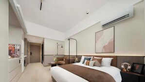 A modern hotel room with a large bed, bedside tables, an air conditioning unit, and a painting on the wall. - Suisse Place Olympic Sports Center Nanjing (Nanjing)