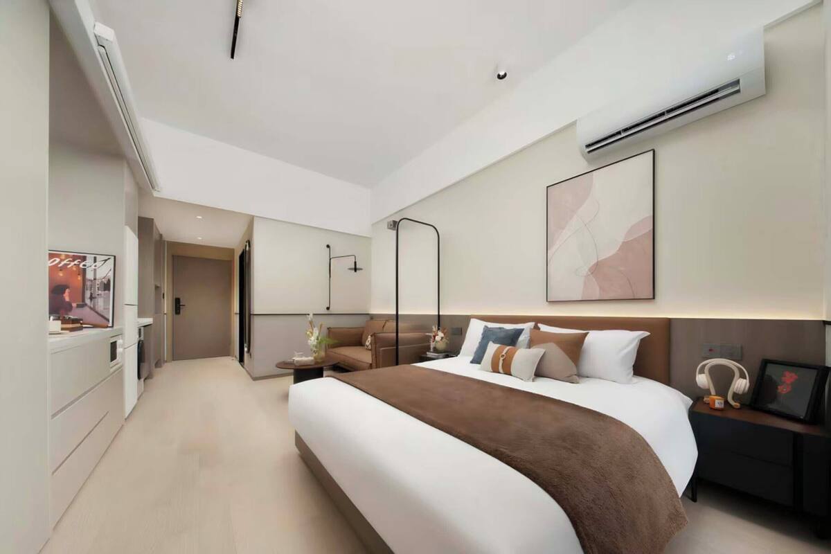 Een moderne hotelkamer met een groot bed, nachtkastjes, een airconditioning en een schilderij aan de muur.