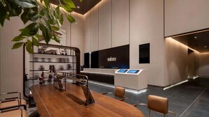 A modern hotel reception area with a reception desk, seating area, and a plant. - Suisse Place Olympic Sports Center Nanjing (Nanjing)