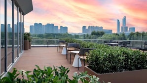 A rooftop terrace with outdoor seating, a city skyline view, and a sunset sky. - Suisse Place Olympic Sports Center Nanjing (Nanjing)