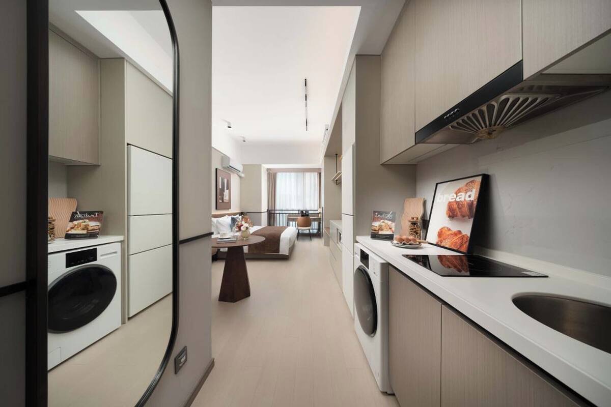 Een moderne keuken met een inbouwoven, een spoelbak en een eethoek met een tafel en stoelen.