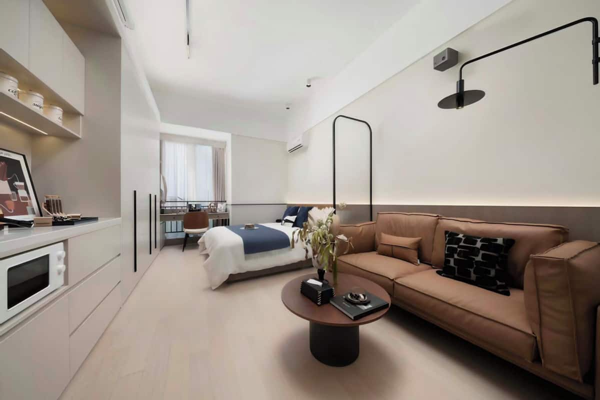 Een moderne hotelkamer met een bed, een bank, een salontafel en een bureau met een stoel.
