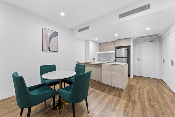 A modern kitchen with a central island, white cabinetry, and stainless steel appliances. - Lucid Apartments by CLLIX (South Brisbane)