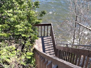 Staircase descends to a serene body of water surrounded by lush greenery.